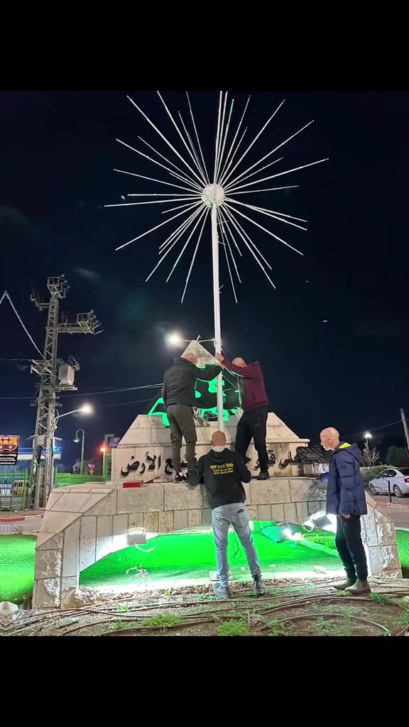צוות מתקין תאורה בכיכר עירונית בשעות הלילה